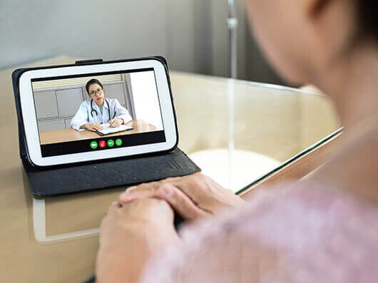 A patient engages in a telehealth consultation with a doctor on a tablet.